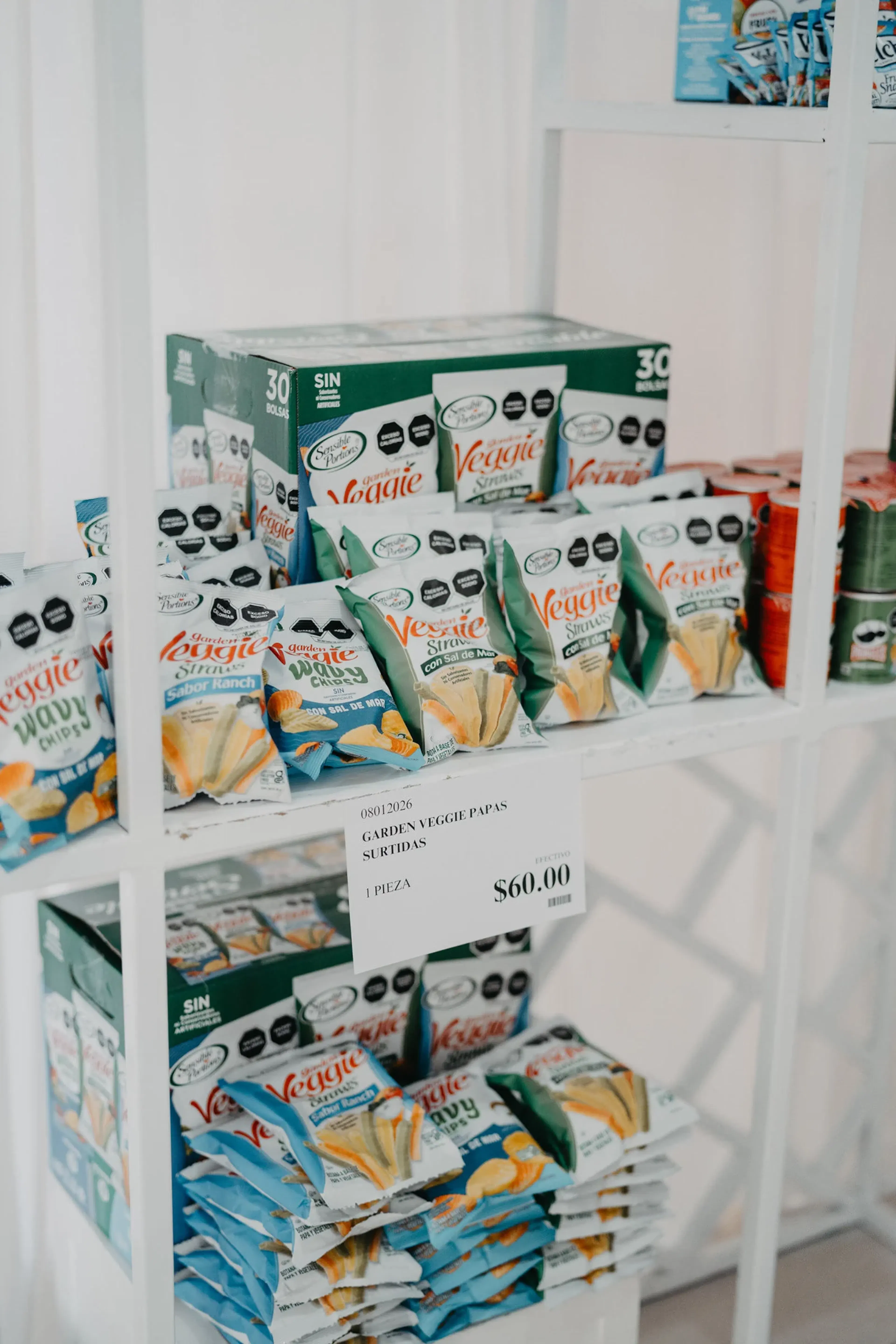 Estantería con varios paquetes de pajitas de verduras de diferentes sabores. El precio indicado es de $60.00. Un ambiente luminoso y organizado.