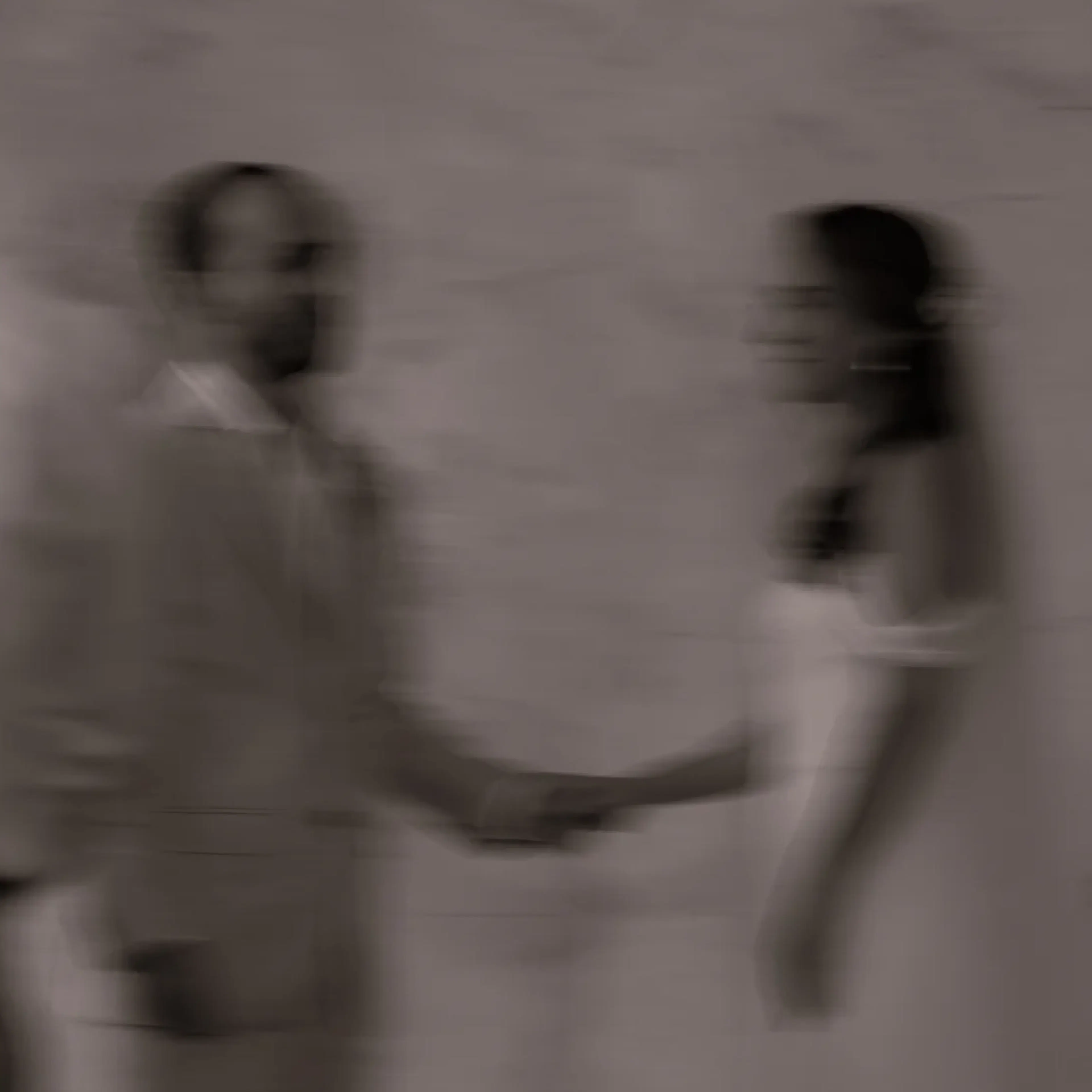 Imagen borrosa en blanco y negro de una ceremonia nupcial. Una pareja se toma de la mano, mirándose, rodeada de velas encendidas, creando un ambiente romántico.