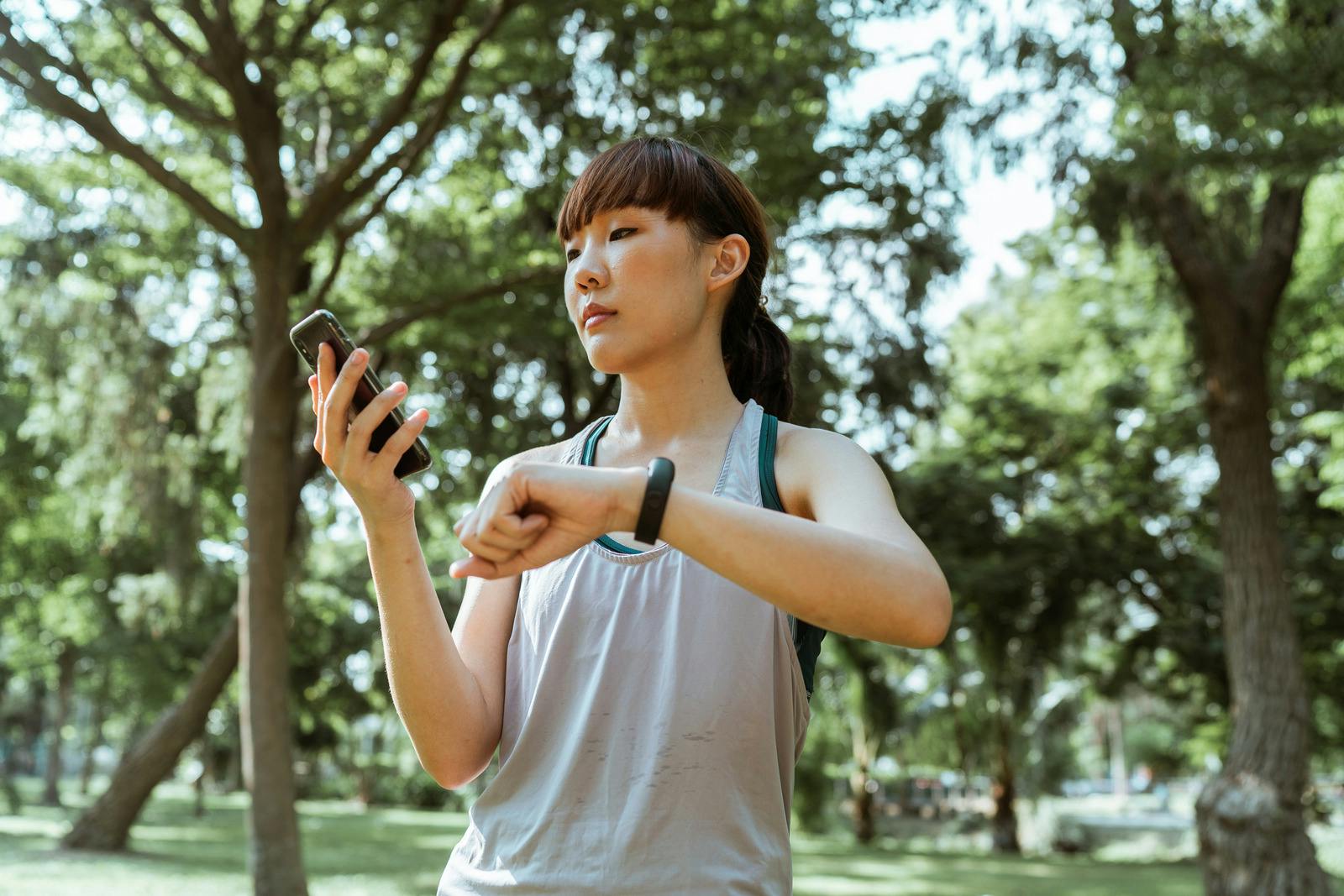 woman checking her phone and fitbit outside 
