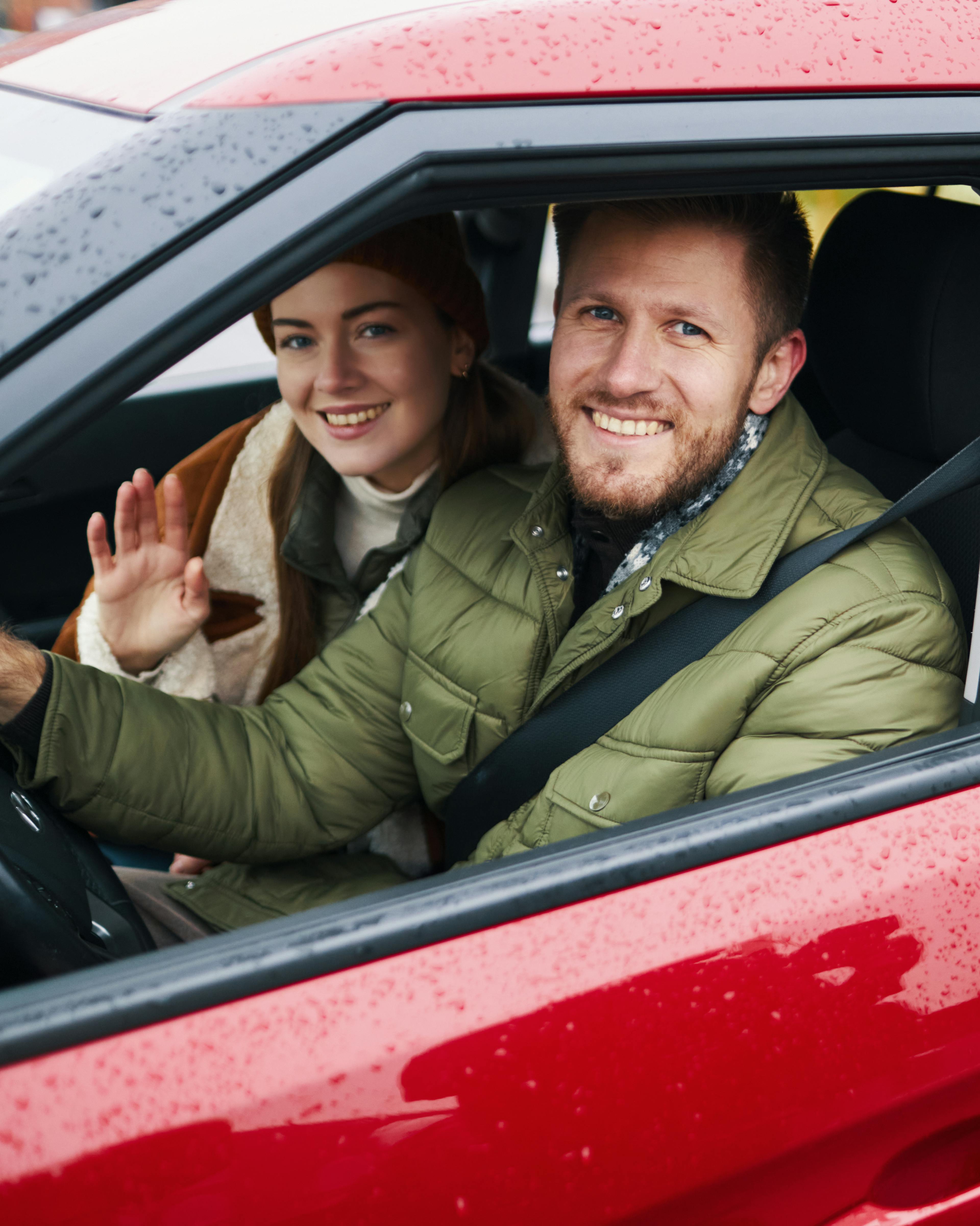Smiling family enjoying road trip in red car