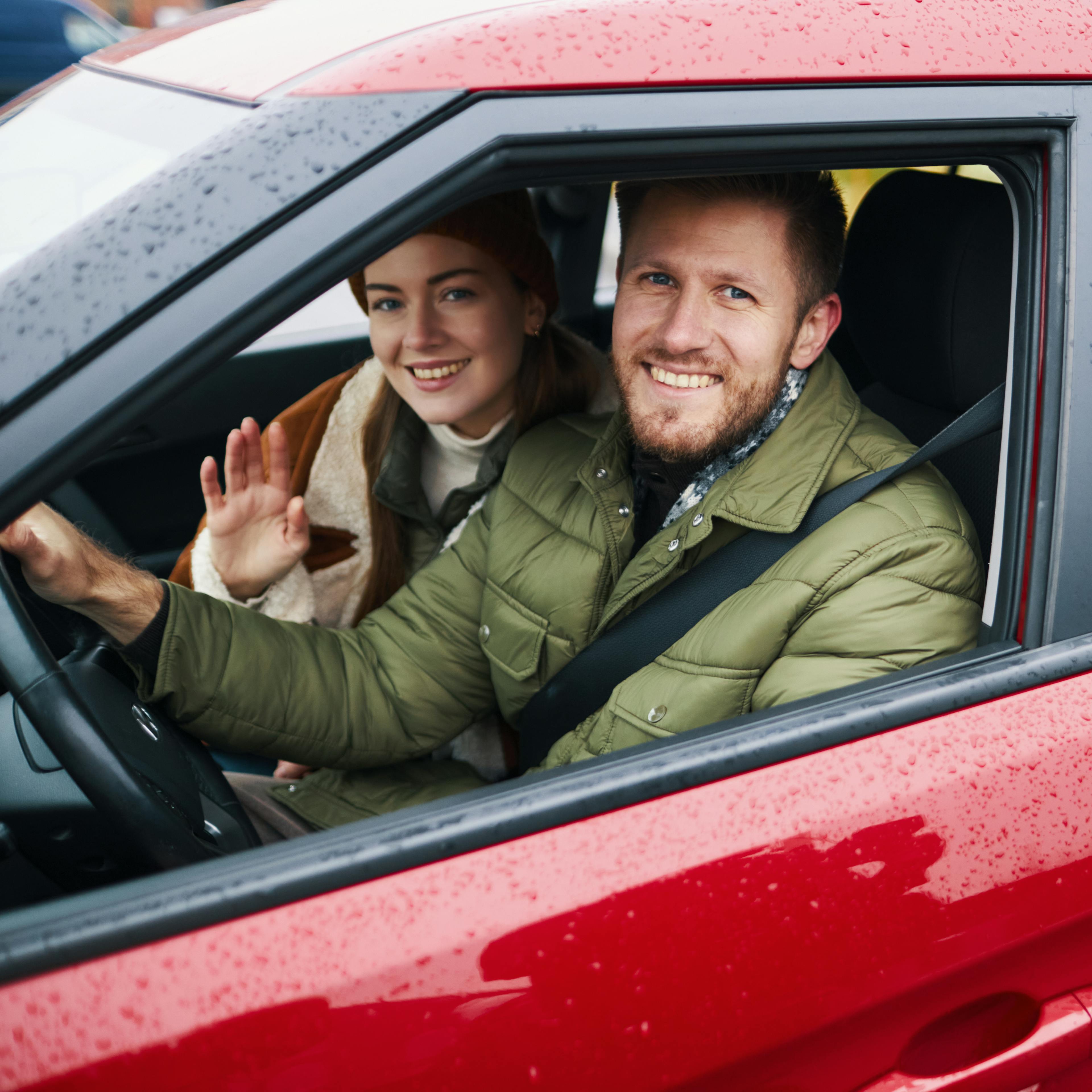 Smiling family enjoying road trip in red car