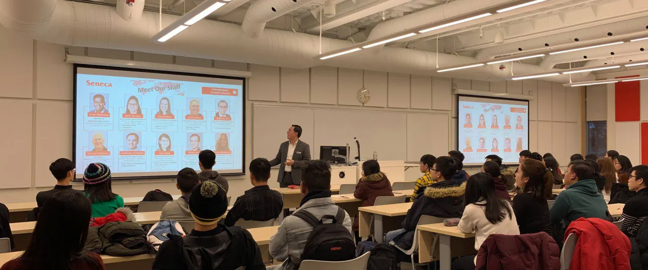 A group of students attentively listen to a speaker in a VAS' orientation