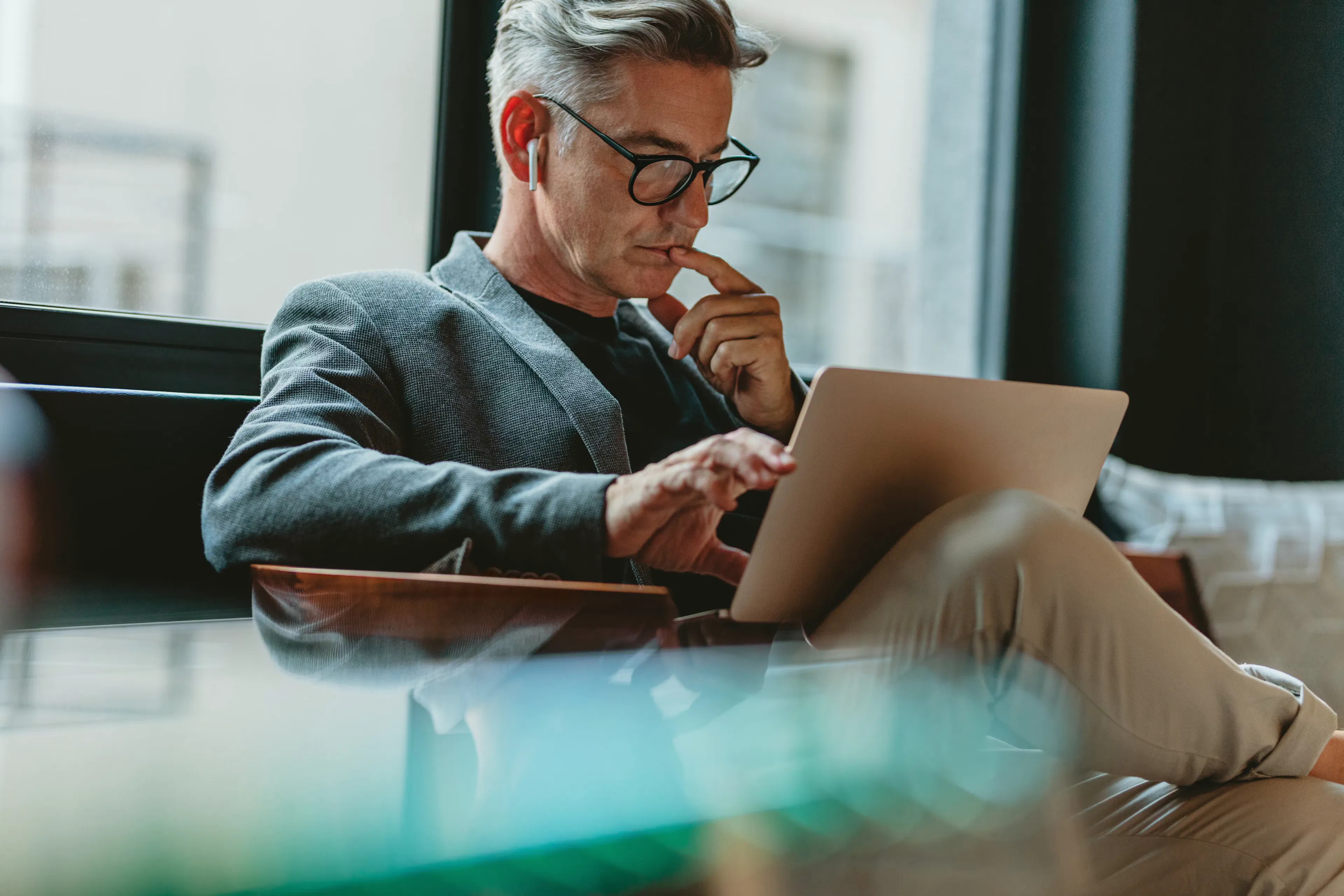 Man seated by a window working on a laptop.