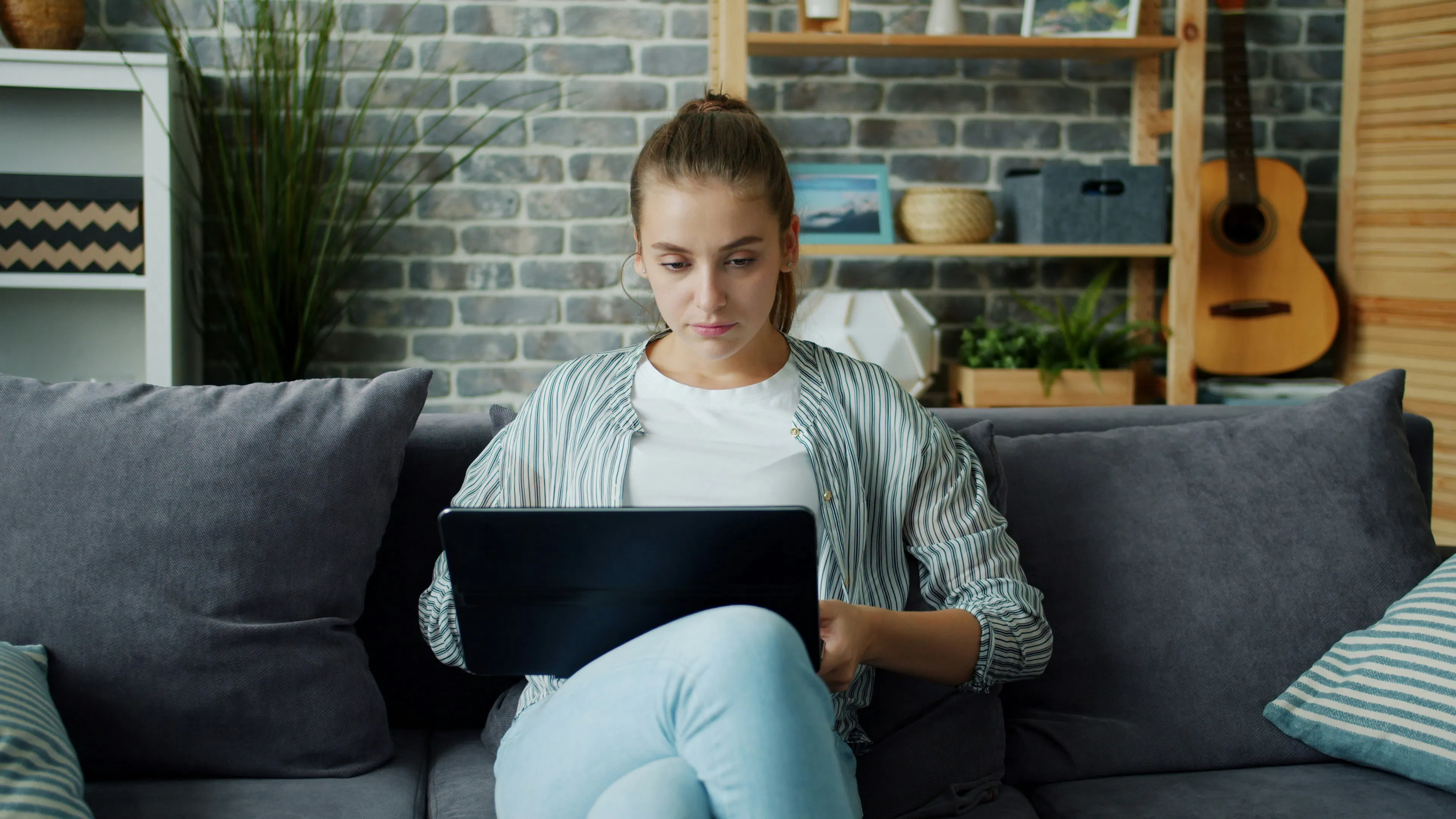 Person sitting on a couch using a laptop, representing choosing a crypto platform in Canada
