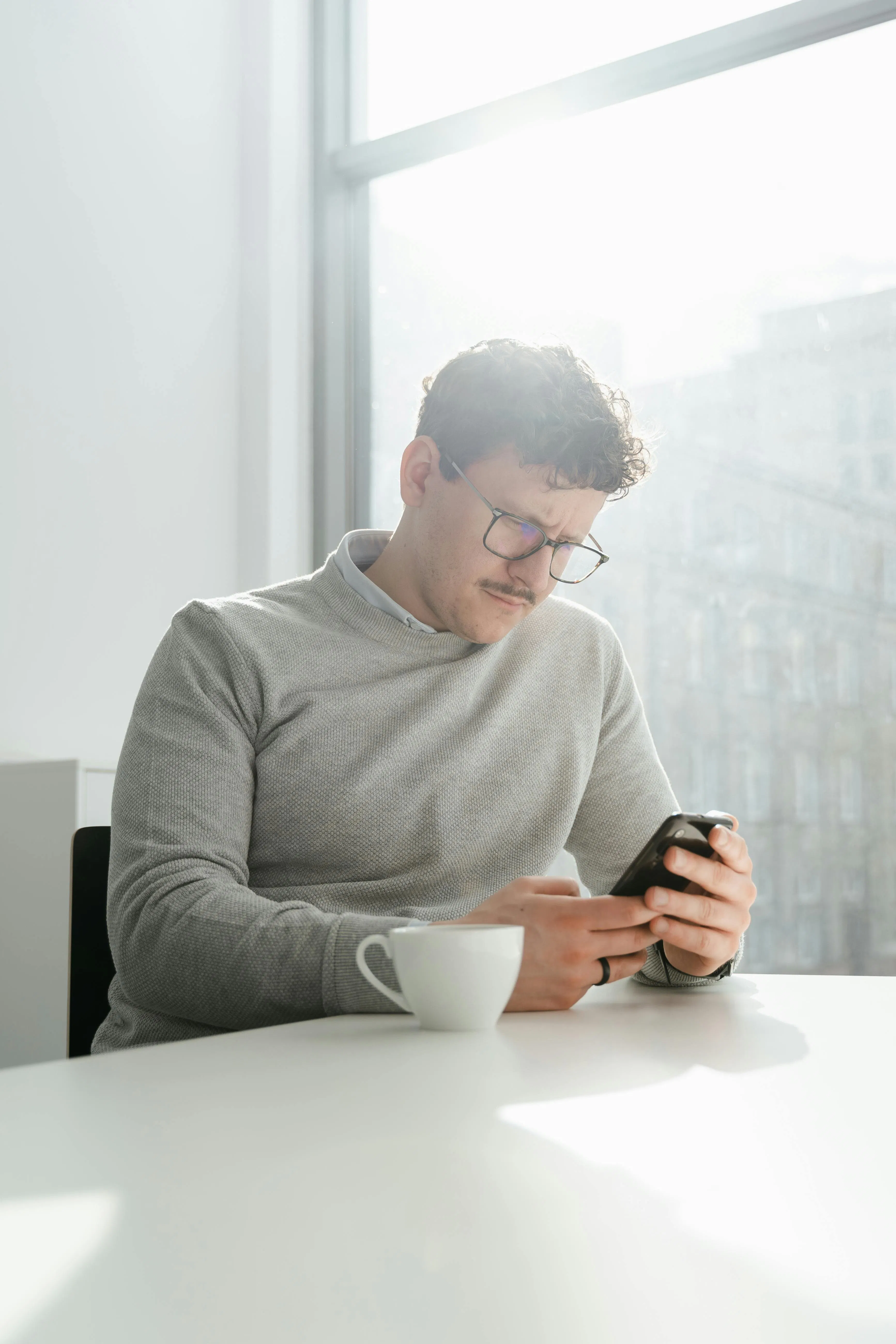 Person using a smartphone at a kitchen table, representing buying Bitcoin in Canada