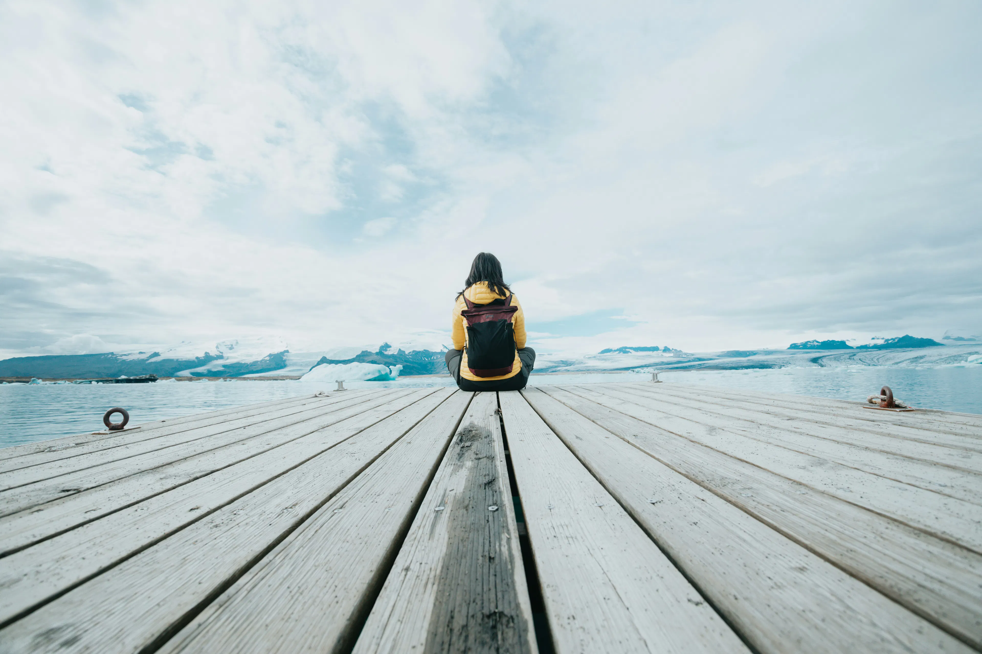 Woman sitting on a dock overlooking the water, representing independence and control.