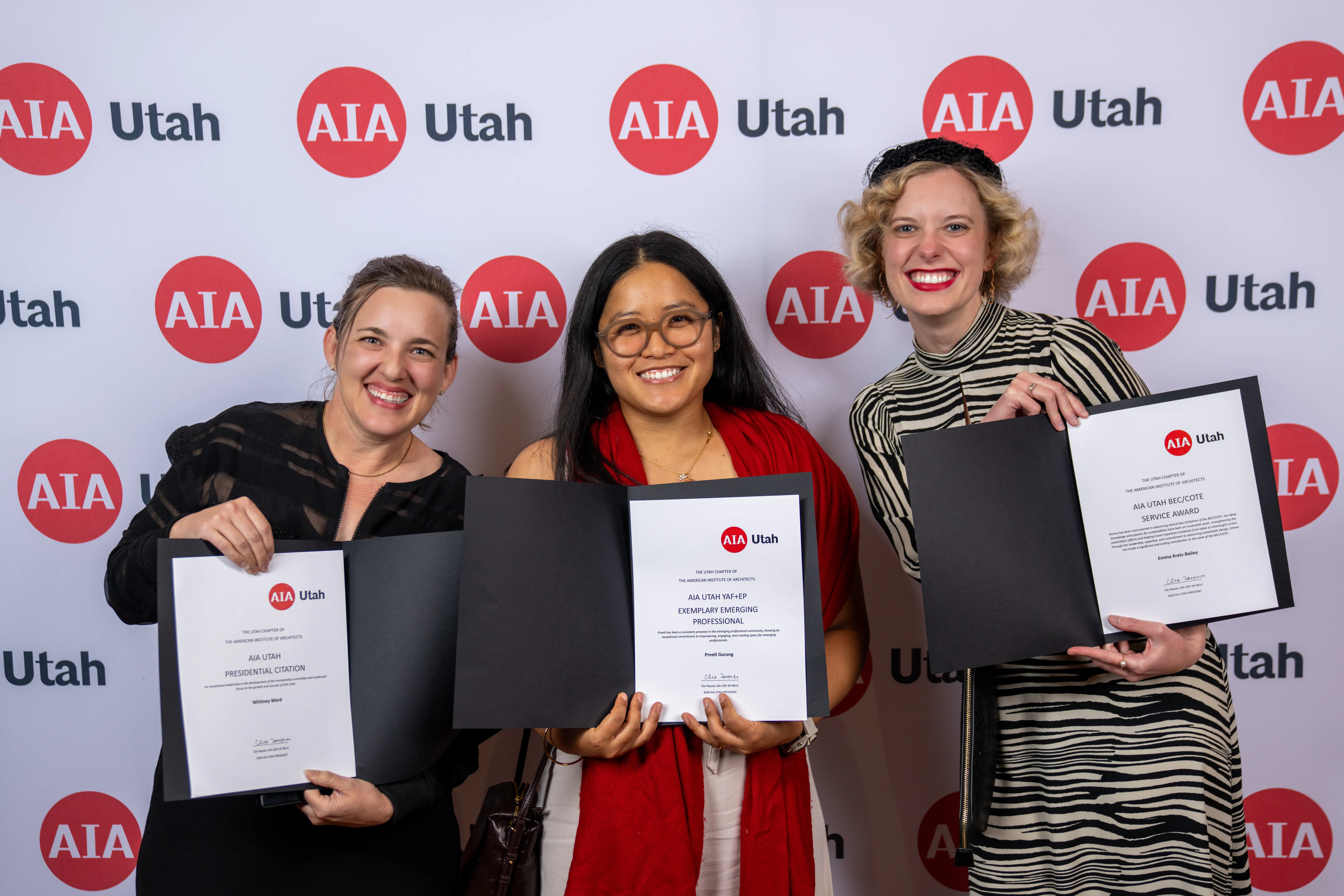 Whitney Ward, Preeti Gurung, and Emma Kratz-Bailey with their 2026 AIA Utah awards in front of a media wall.