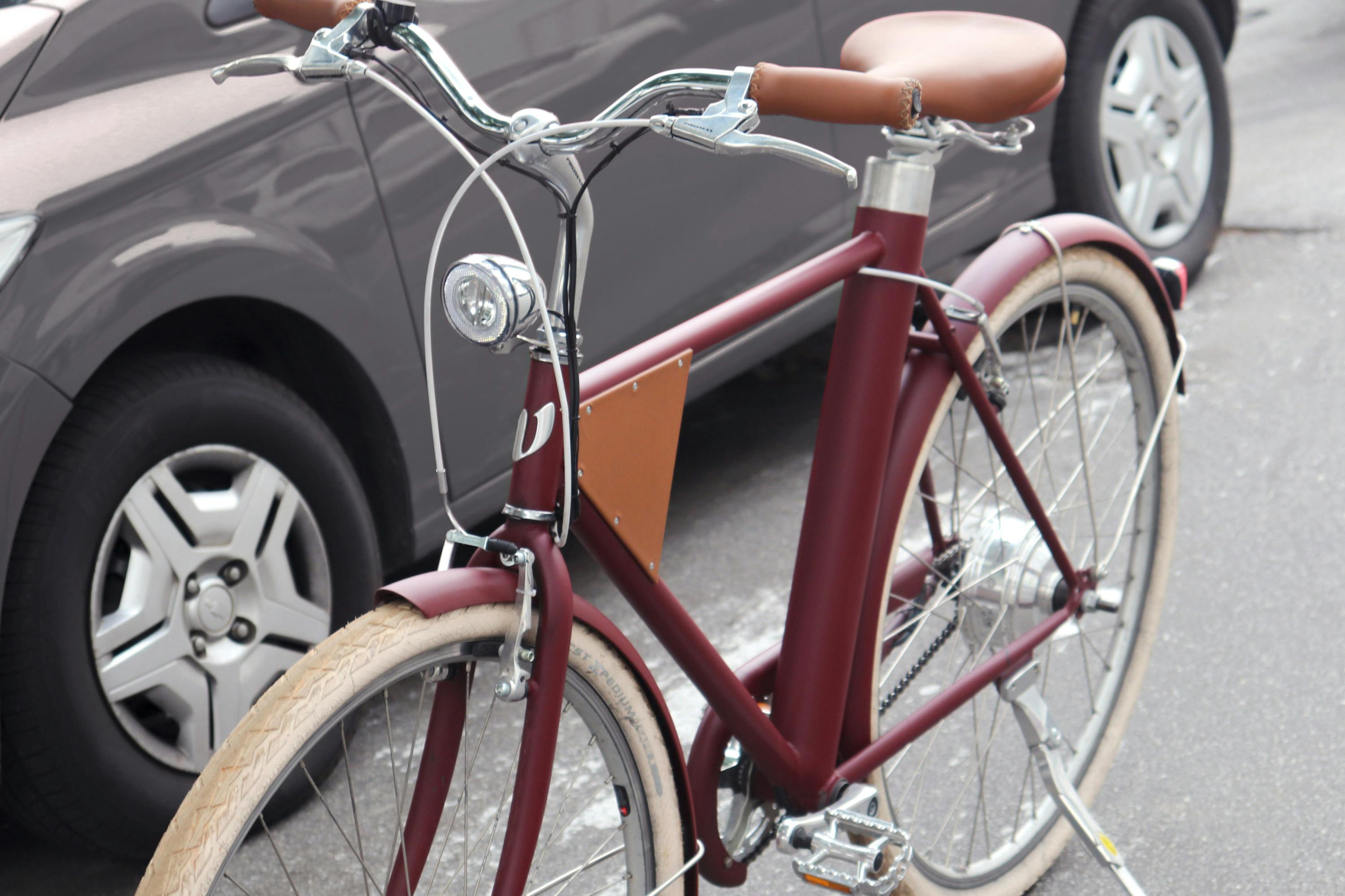 Bicicleta Vela vinho em frente a carro popular cinza