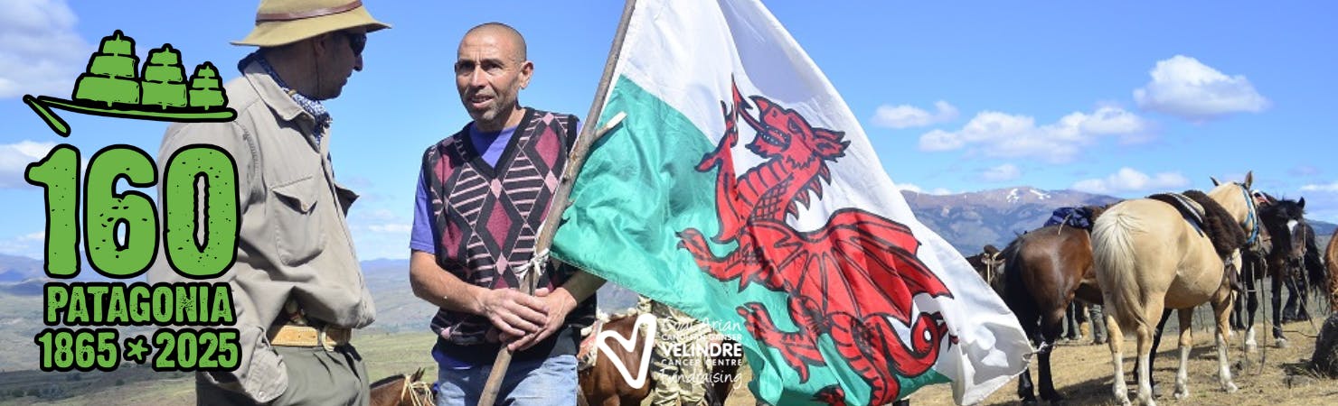 Banner for the Patagonia trek that reads 160, 1865 to 2025. Image of two smiling people with a Welsh flag atop the summit.