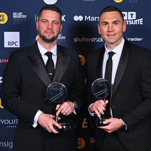 Craig in a dashing suit, holding an award beside his friend.
