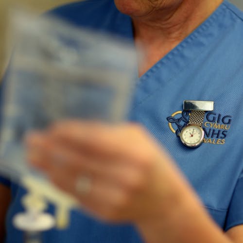 A close-up shot of badges on the scrubs of an NHS worker.