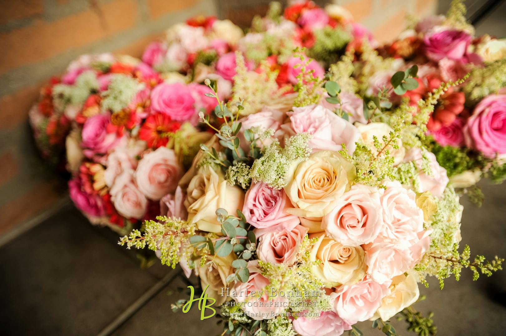 Bouquets of pink and yellow roses, splashed with sprigs of greenery.