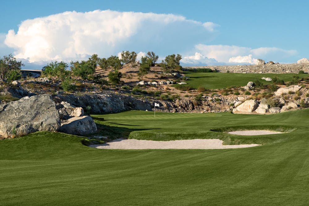 Pretty photo of green fairway, fairway bunkers, and beautiful clouds in the background.