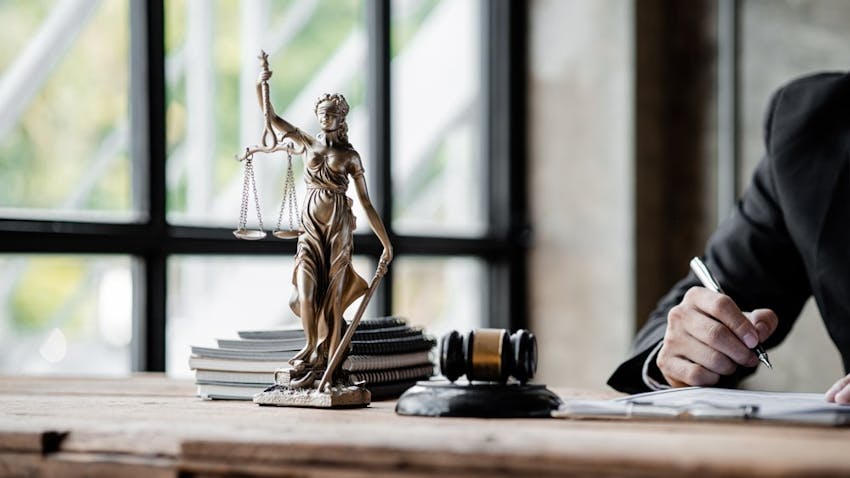 Law Statue On A Table Next To Judges Hammer