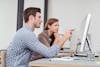 Man Pointing On A Monitor For A Woman