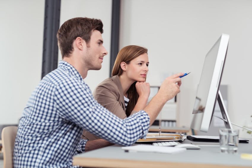Man Pointing On A Monitor For A Woman
