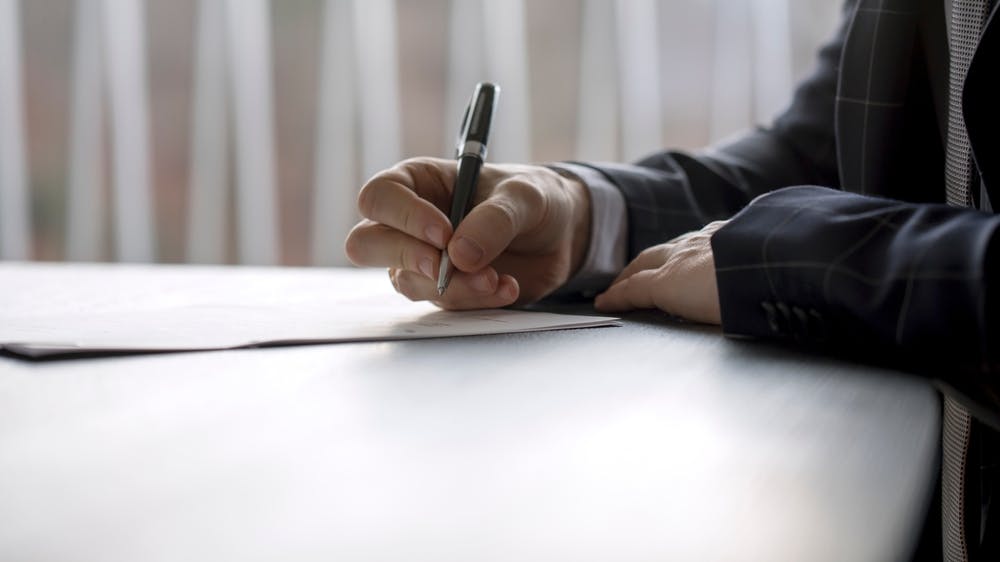 Photo of a man writing papers sitting at the desk