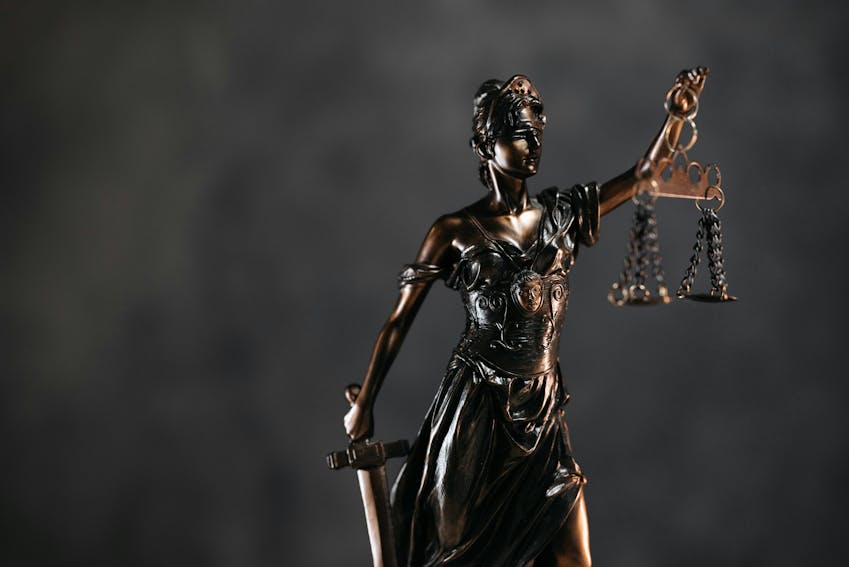 Bronze statue of Lady Justice holding scales and a sword, symbolizing fairness and impartiality in the legal system.