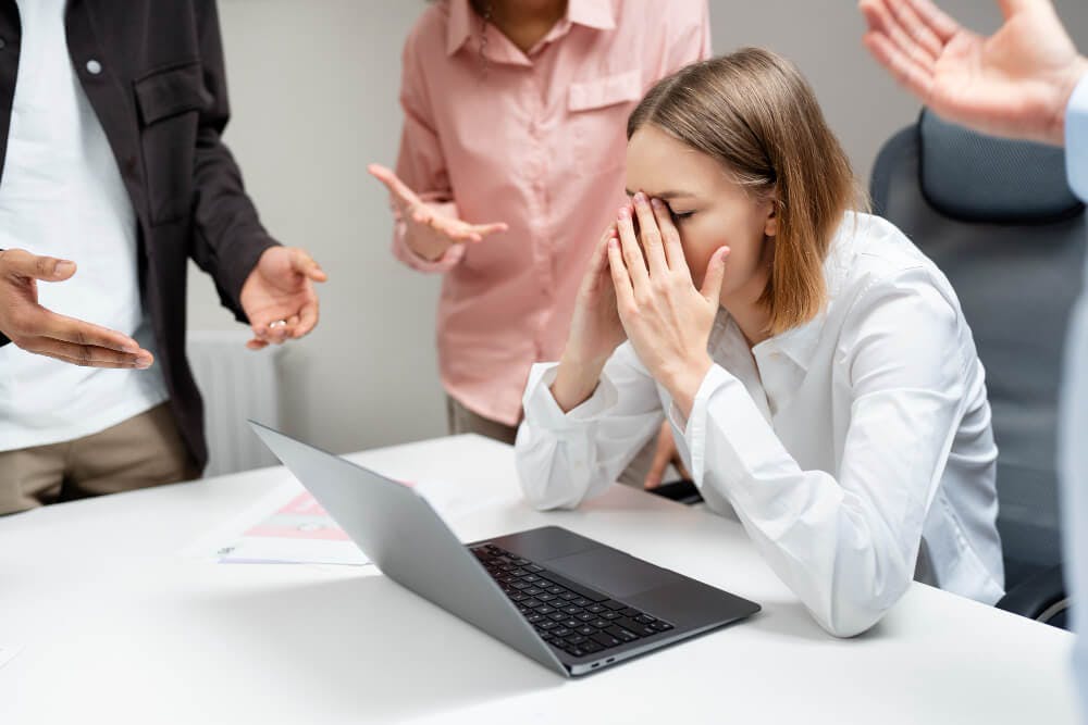Person In Front of a Laptop Getting Pressured by Their Coworkers