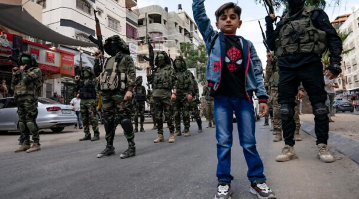 Children stand with Hamas terrorists as they march through the streets
