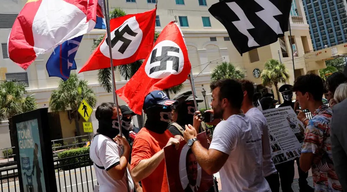 People waving Nazi swastika flags argue with conservatives during a protest outside the Tampa Convention Center