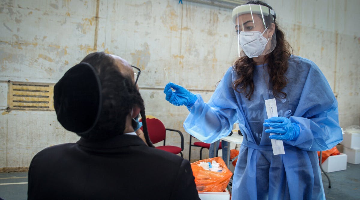 A health worker takes a swab sample at a COVID-19 testing facility