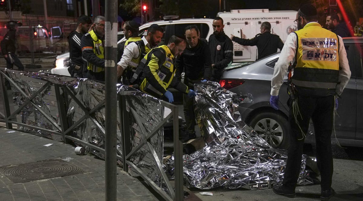 Members of Zaka Rescue and Recovery team check a body after a terror shooting attack near a synagogue in Jerusalem