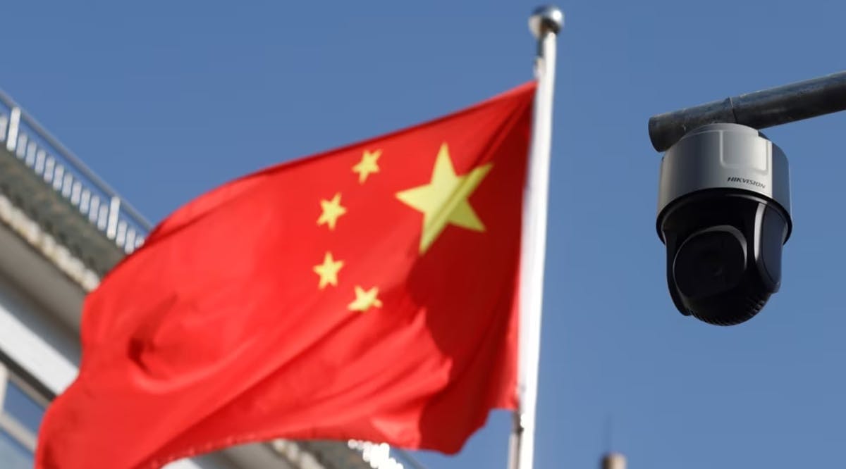 A surveillance camera overlooking a street hangs next to a Chinese flag in Beijing, China