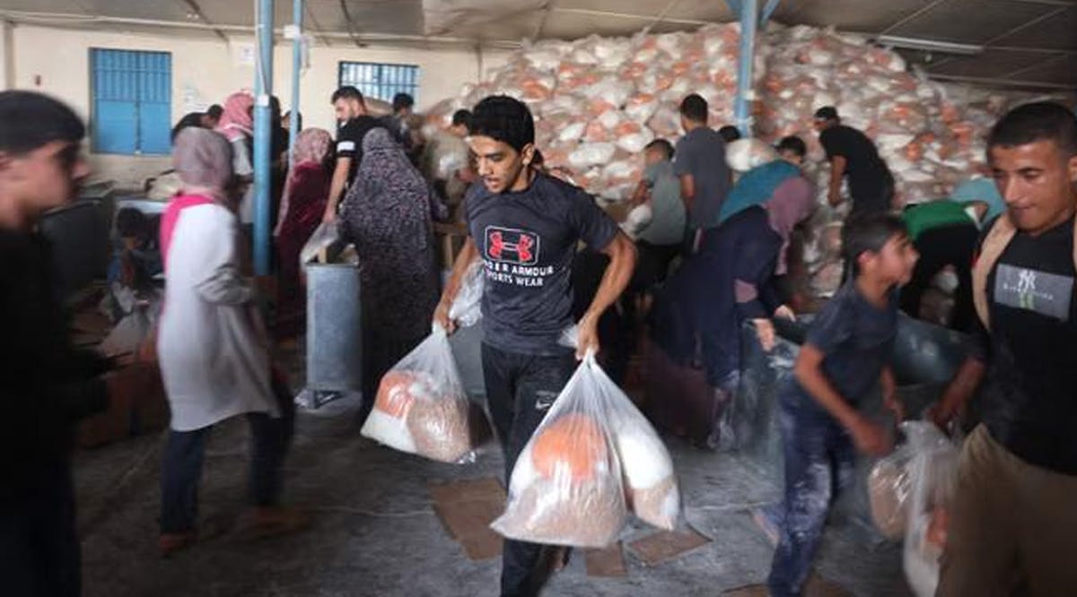 People carrying boxes and large bags out of a warehouse