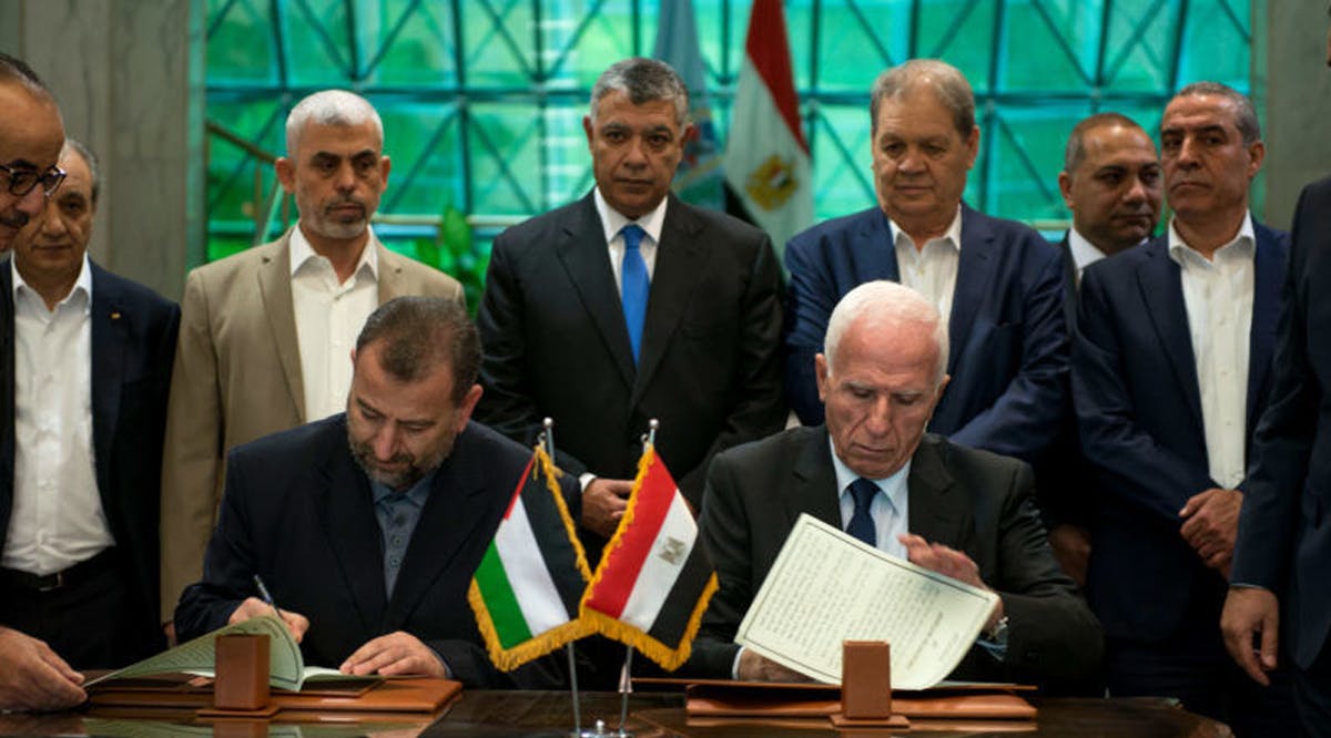 Palestinian member of Fatah Central Committee, Azam al-Ahmed (R), and Hamas deputy head of the politburo Saleh al-Aruri (L) sign an agreement between the two Palestinian factions