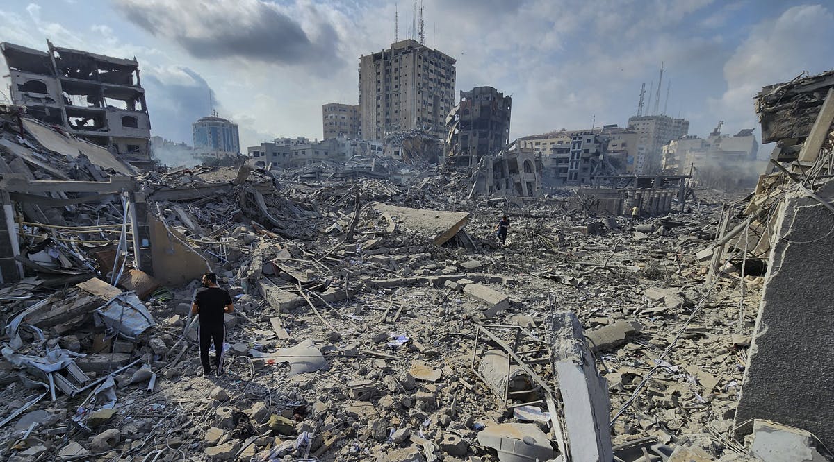 A Palestinian walks through the destruction by Israeli bombing in Gaza City
