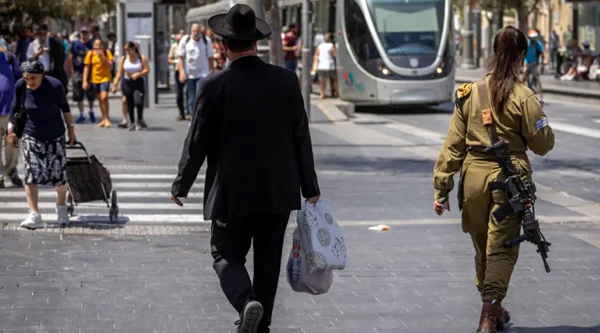 An ultra-Orthodox Jewish man walks next to an Israeli female soldier on Jaffa Road