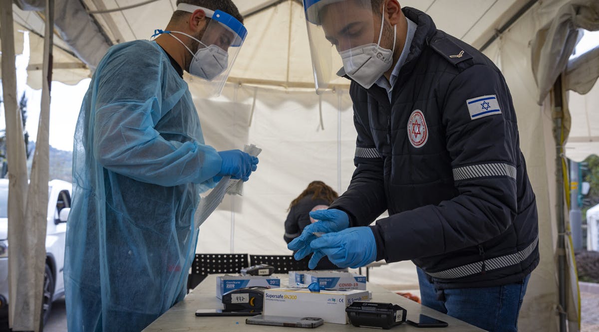 Workers take a COVID-19 rapid antigen test from Israelis, at a Magen David Adom drive through complex in Jerusalem