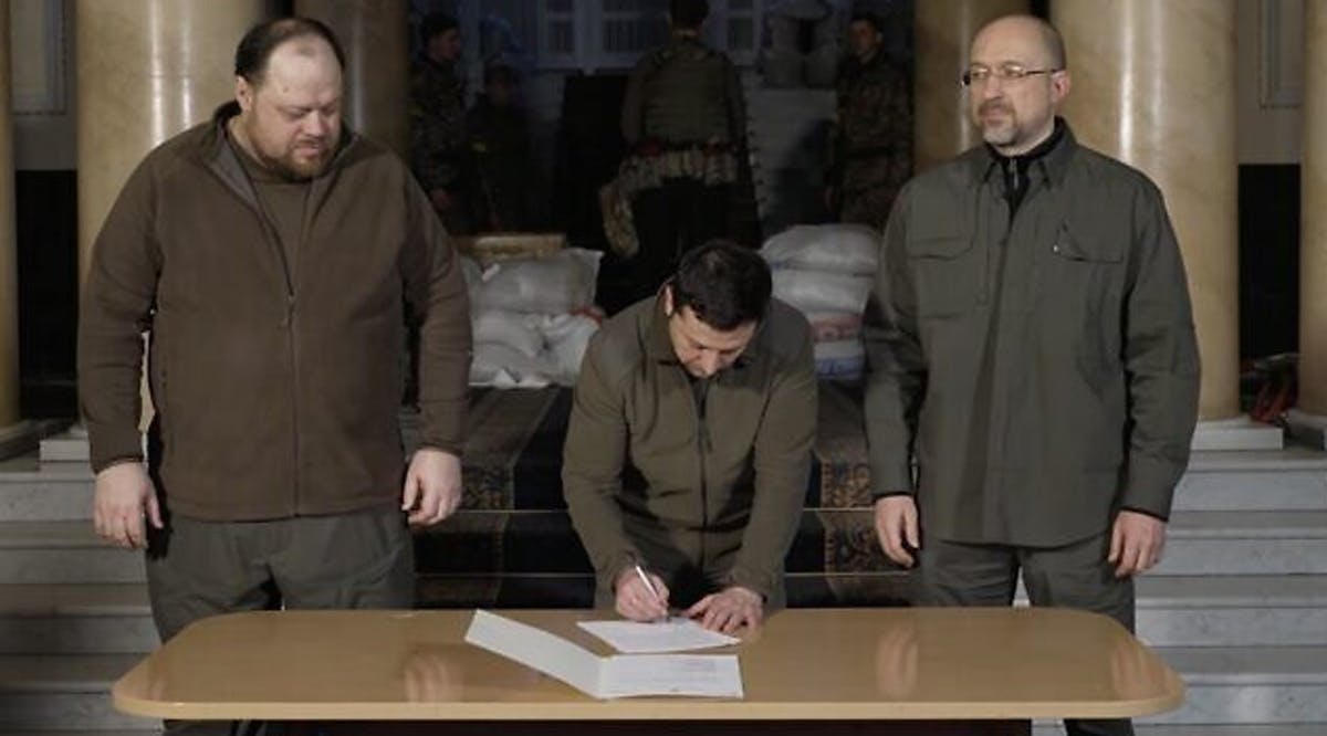 Ukrainian President Volodymyr Zelensky (center) signs an application for Ukraine to join the European Union