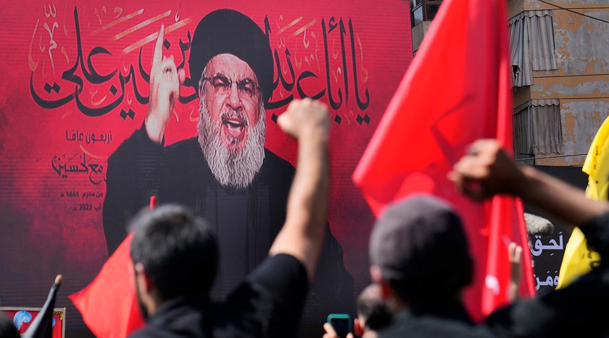 Hezbollah terror leader Hassan Nasrallah speaks via a video link, as his supporters raise their hands, during the Shiite holy day of Ashoura, in a southern suburb of Beirut, Lebanon