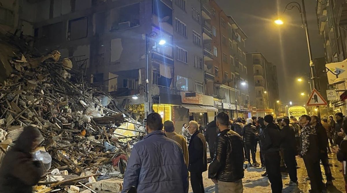 People gather around a collapsed building in Pazarcik, in Kahramanmaras province, southern Turkey