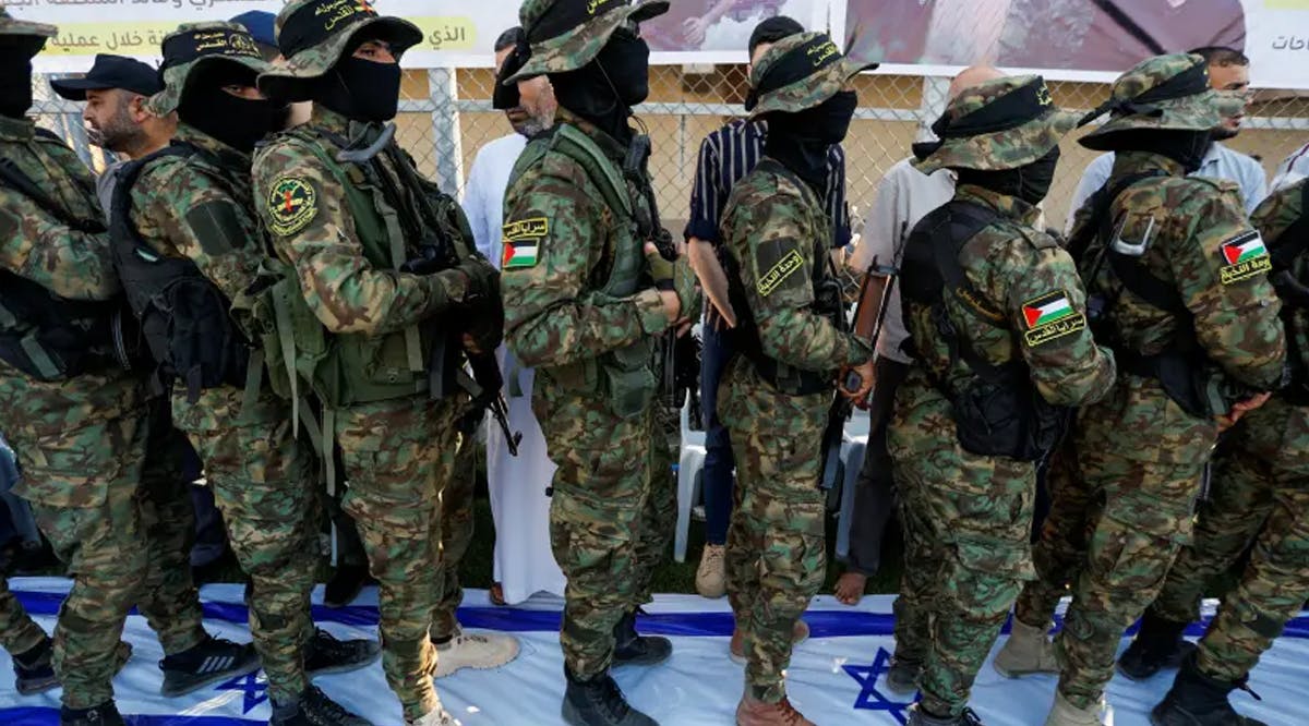 Palestinian Islamic Jihad militants stand on a banner depicting the flag of Israel