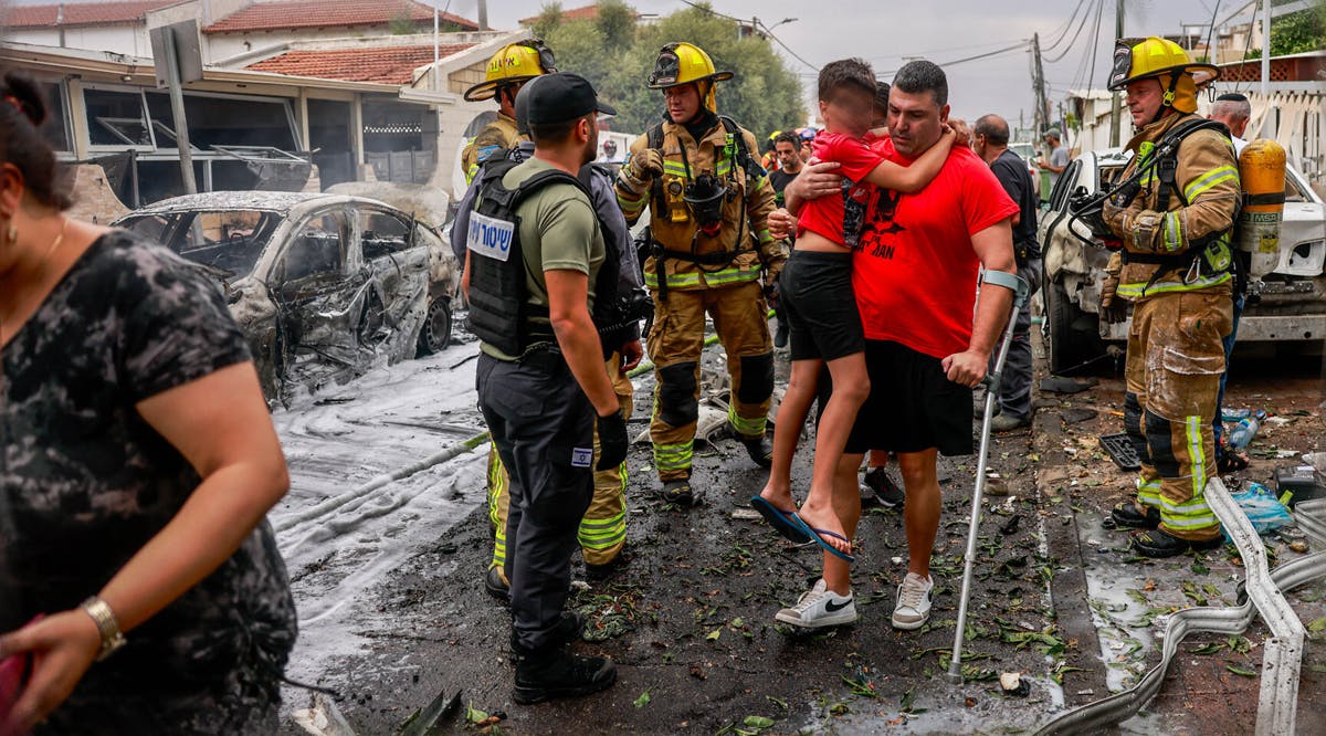 An Ashkelon resident and his son make their way to safety after a rocket fired from the Gaza Strip by Palestinian terrorists hit a building