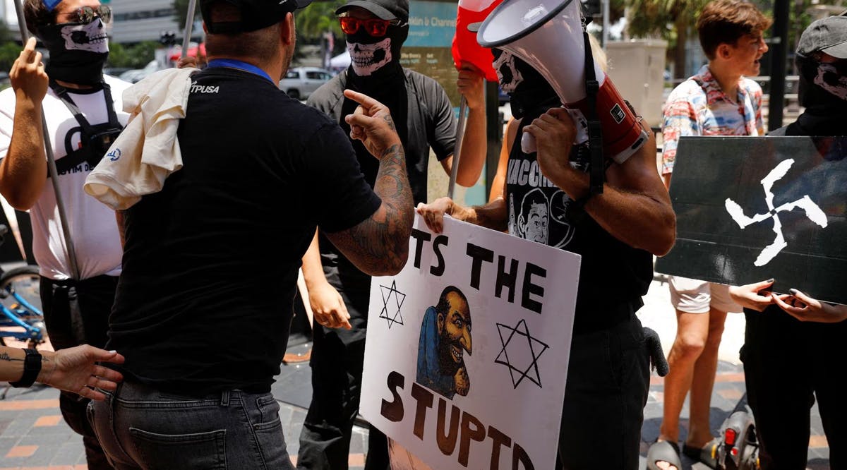 People wearing antisemitism and nazi symbols argue with conservatives during a protest