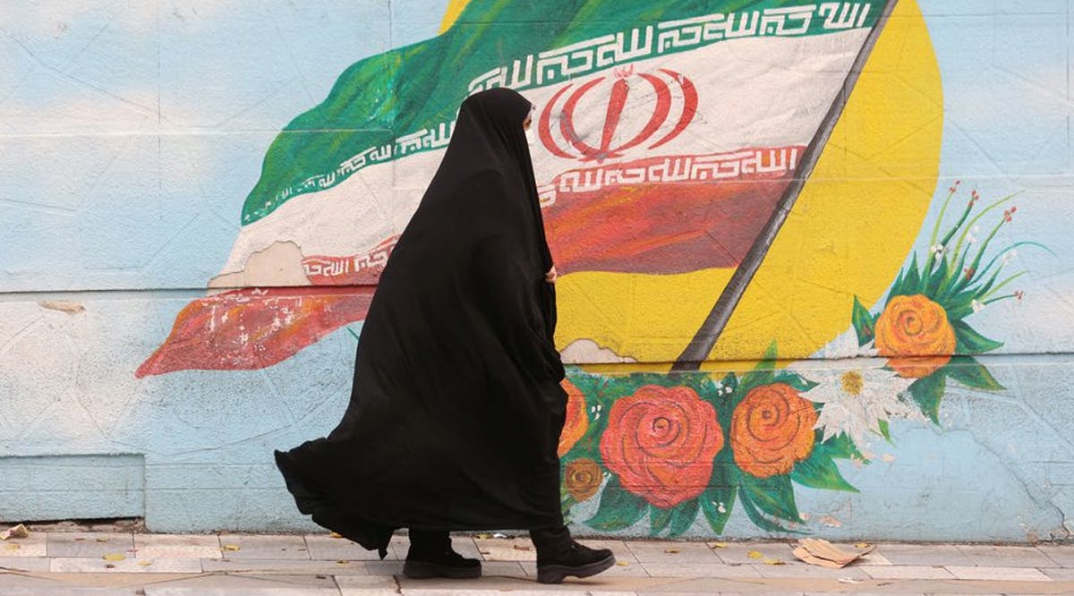 A woman walks after the morality police shut down in a street in Tehran, Iran