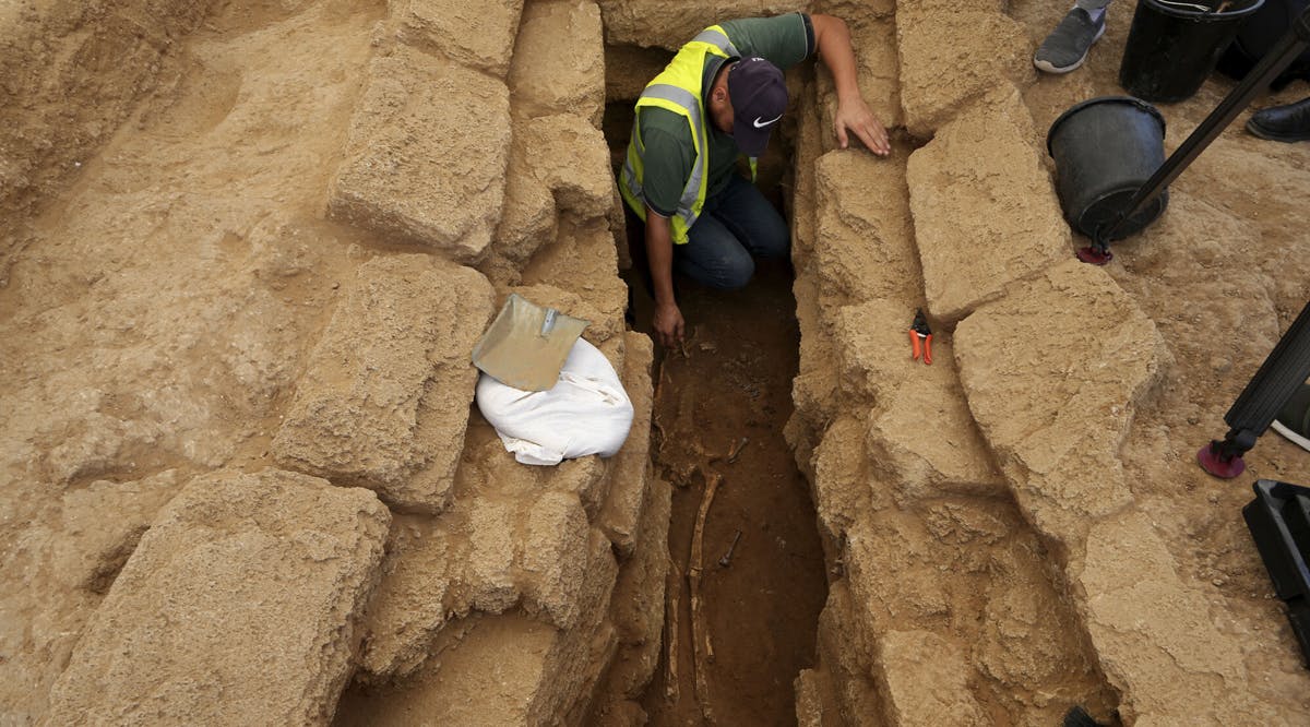 A Palestinian archaeologist removes the sand from a skeleton in a grave at a Roman-era cemetery in Jebaliya northern Gaza Strip
