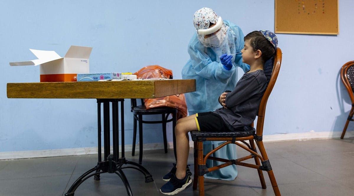 A Magen David Adom worker takes a swab sample for a COVID-19 rapid antigen test from a young boy, at a testing center in Jerusalem