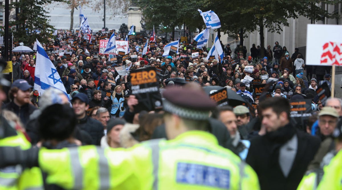 Demonstrators wave Israeli flags at a march against the rise of antisemitism in the UK