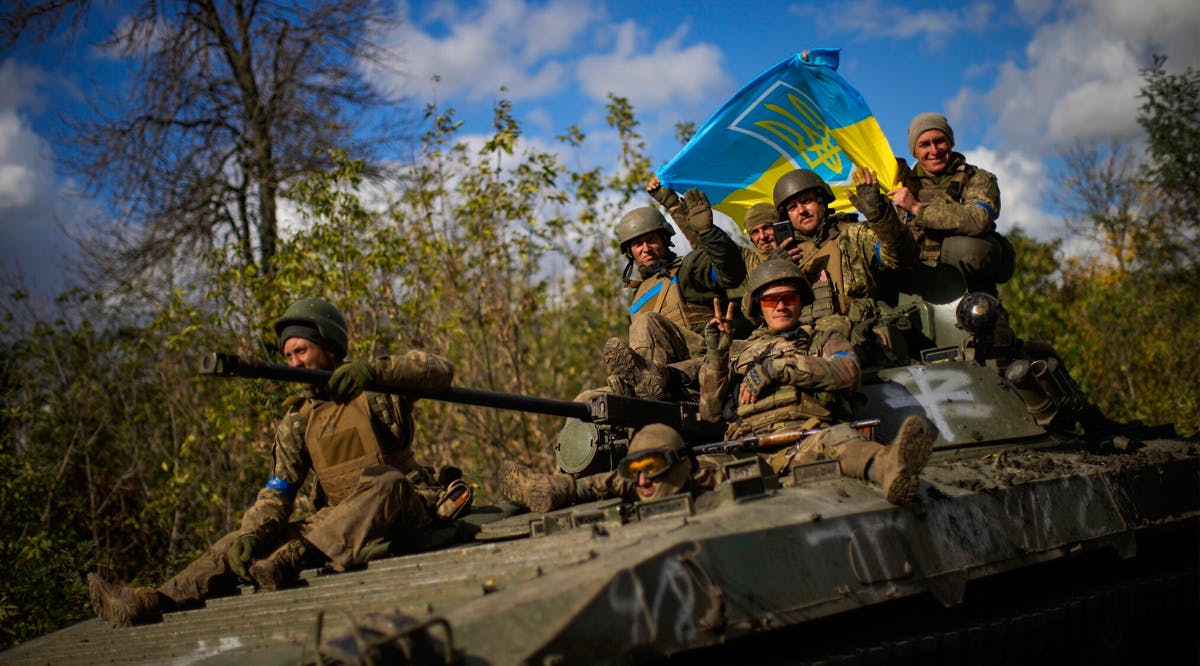 Ukrainian soldiers sit on an armored vehicle as they drive on a road between Izium and Lyman, recently retaken areas in Ukraine