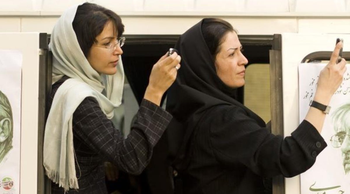 Iranian women take a picture of a presidential candidate with their mobile phones in Tehran , Iran