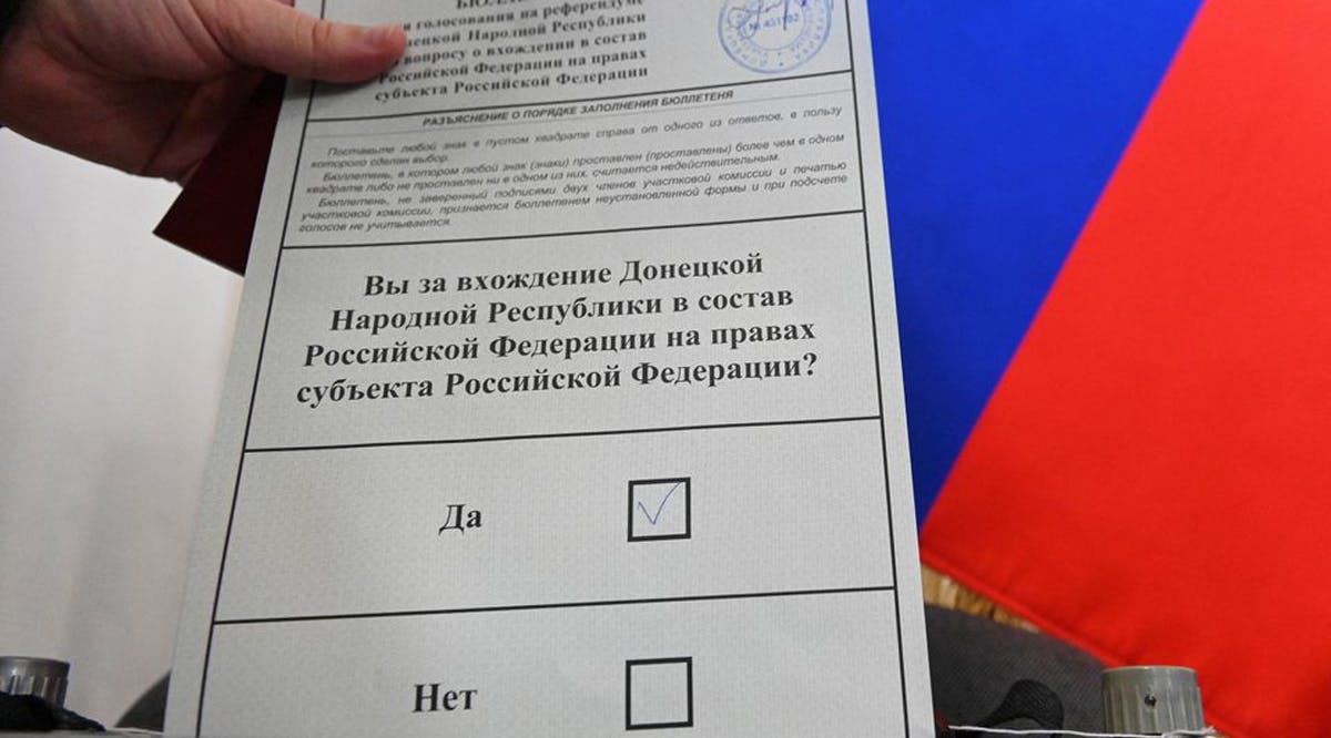 A voter demonstrates a ballot to journalists