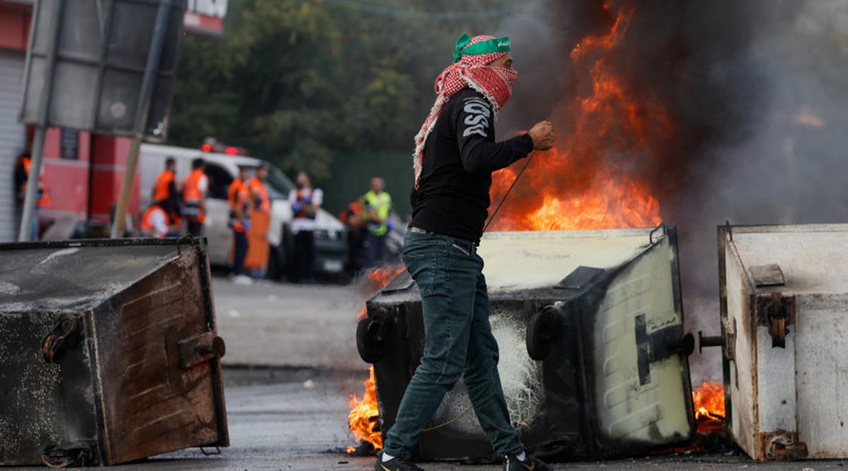 Palestinian walks next to the fire during clashes with Israeli forces near Ramallah in the West Bank