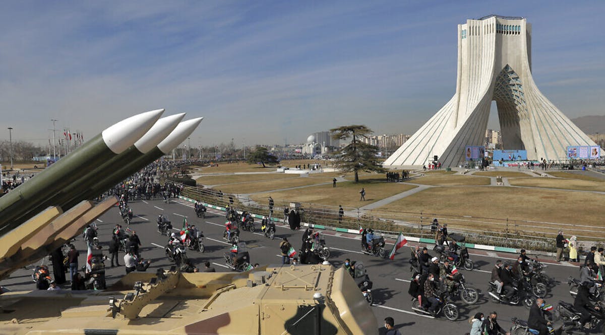 Iranians drive past missiles