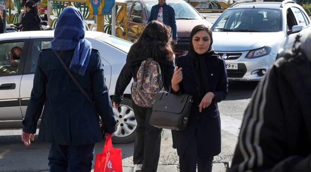 A young Iranian woman crosses a street without wearing her mandatory Islamic headscarf in Tehran, Iran