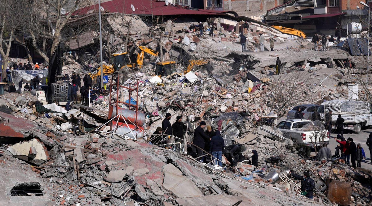 People stand on a destroyed building, in Kahramanmaras, southern Turkey